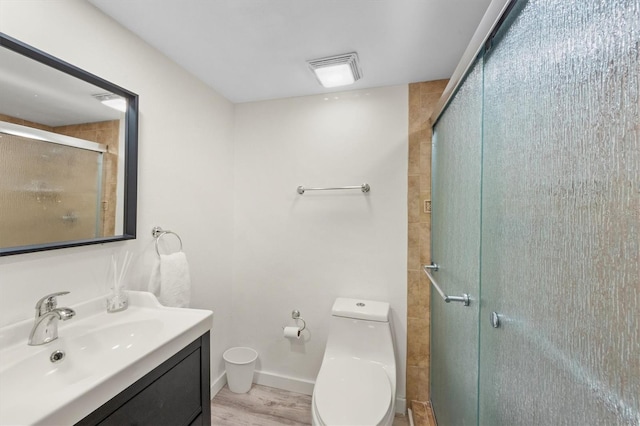 bathroom featuring toilet, vanity, wood-type flooring, and a shower with door