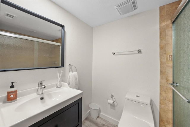 bathroom with toilet, vanity, a shower with door, and hardwood / wood-style flooring