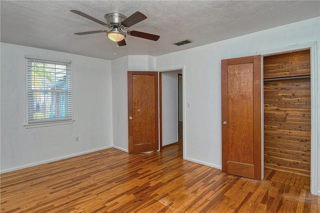 unfurnished bedroom featuring a textured ceiling, ceiling fan, a closet, and wood-type flooring