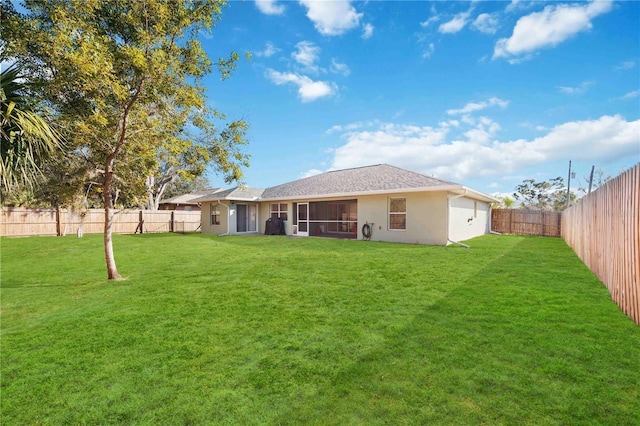 rear view of house featuring a yard and a sunroom