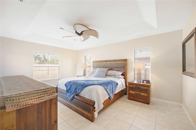 tiled bedroom with ceiling fan and a raised ceiling