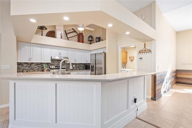 kitchen with white cabinetry, decorative backsplash, light tile patterned floors, kitchen peninsula, and stainless steel appliances