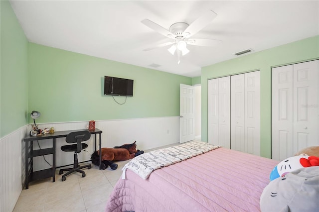 bedroom featuring light tile patterned floors, two closets, and ceiling fan