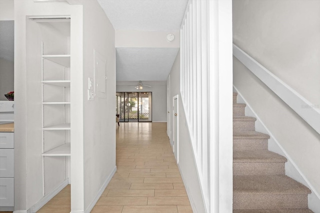 hall featuring wood tiled floor, baseboards, stairway, and a textured ceiling