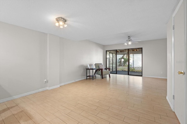 empty room with ceiling fan, a textured ceiling, baseboards, and light wood-style floors