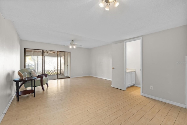 spare room with light wood-style flooring, a textured ceiling, baseboards, and a ceiling fan