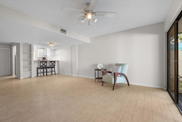 living area with a ceiling fan, light wood-type flooring, visible vents, and baseboards