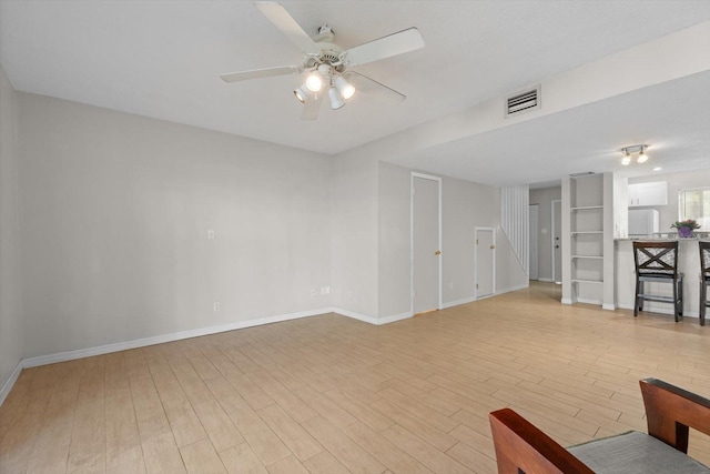 interior space featuring a ceiling fan, baseboards, and light wood finished floors