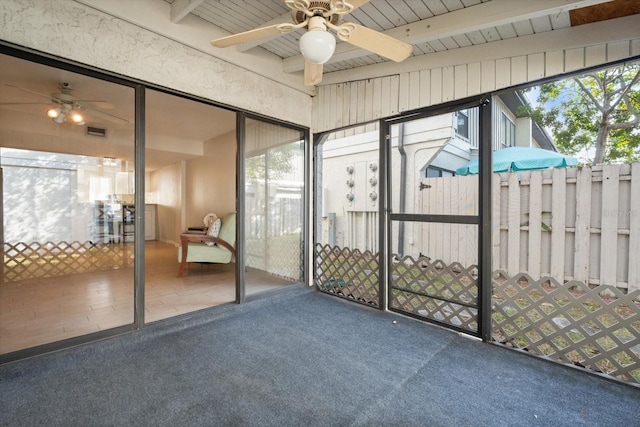 unfurnished sunroom featuring visible vents, beam ceiling, and a ceiling fan