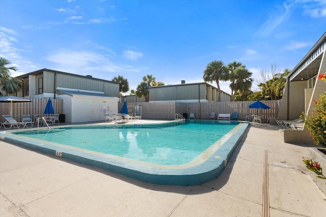 community pool with a patio area and fence