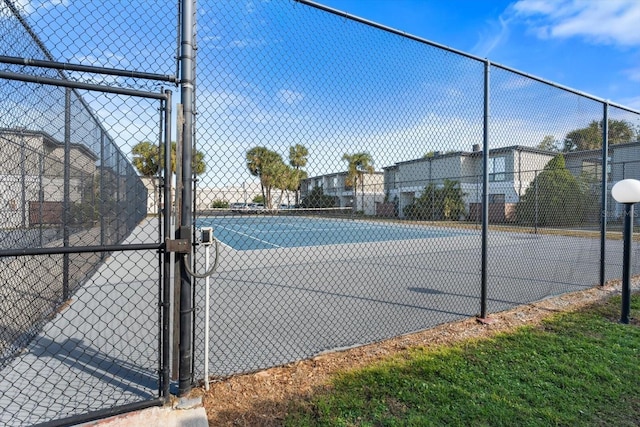 view of tennis court featuring a gate and fence