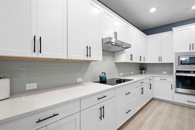 kitchen with white cabinetry, backsplash, light hardwood / wood-style floors, stainless steel appliances, and light stone countertops