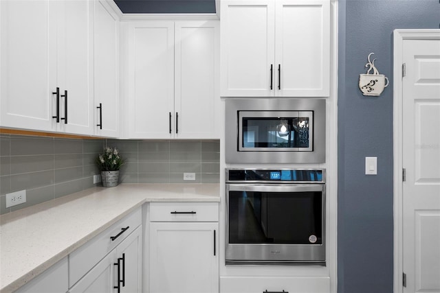 kitchen with white cabinetry, tasteful backsplash, light stone countertops, and appliances with stainless steel finishes