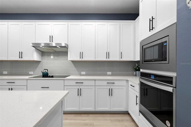 kitchen with white cabinetry, stainless steel appliances, light stone countertops, and light wood-type flooring