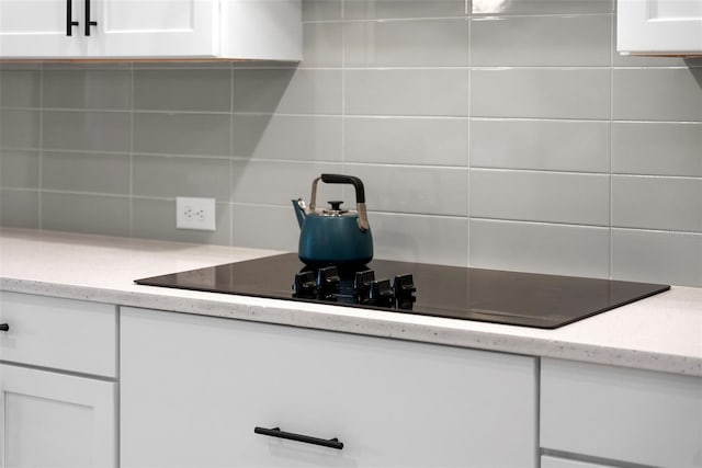 kitchen featuring white cabinetry, black electric cooktop, and decorative backsplash