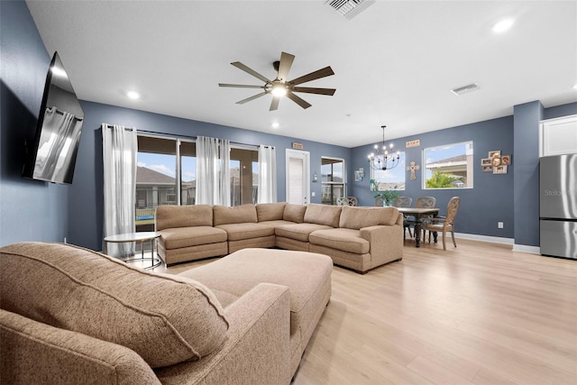 living room with ceiling fan with notable chandelier and light hardwood / wood-style floors