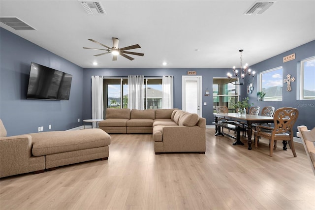 living room with ceiling fan with notable chandelier and light hardwood / wood-style flooring