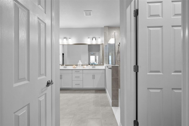 bathroom with tile patterned flooring, vanity, and a shower