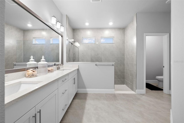 bathroom featuring vanity, toilet, tile patterned flooring, and a tile shower