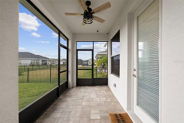 unfurnished sunroom with ceiling fan