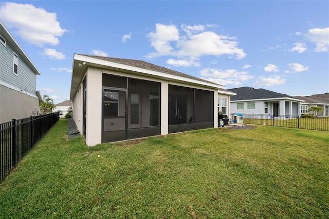 rear view of house featuring a sunroom and a lawn