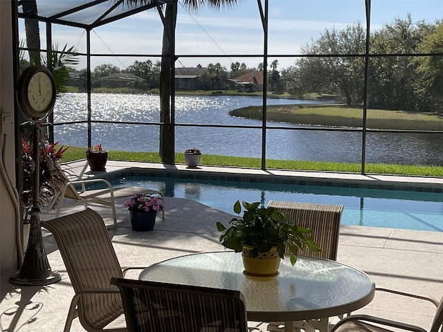 view of swimming pool with a patio area, glass enclosure, and a water view