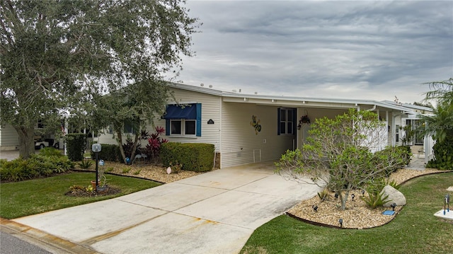 manufactured / mobile home featuring a front yard and a carport