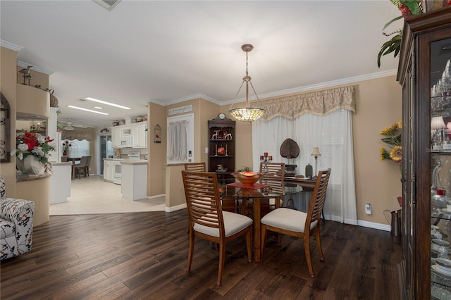 dining space featuring dark wood-type flooring, crown molding, and an inviting chandelier