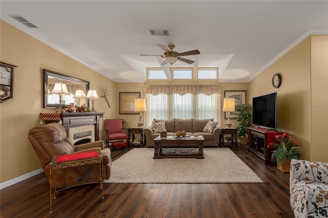 living room featuring ceiling fan, dark wood-type flooring, ornamental molding, and a raised ceiling