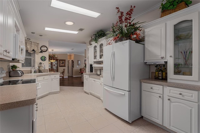 kitchen with crown molding, light tile patterned floors, white appliances, and white cabinetry