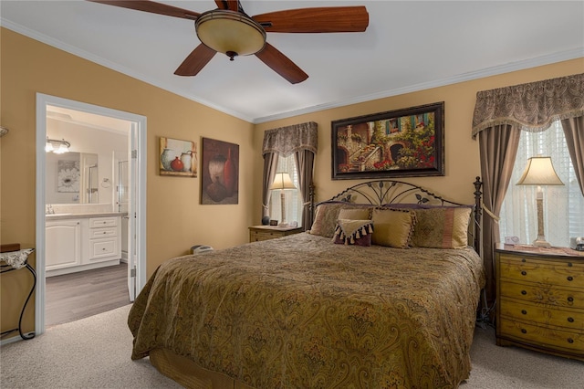 carpeted bedroom featuring ceiling fan, ensuite bath, and crown molding