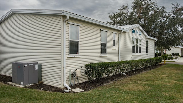 view of side of home featuring central AC and a yard