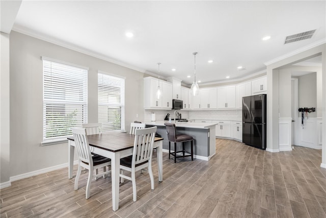 dining room with light hardwood / wood-style floors and crown molding