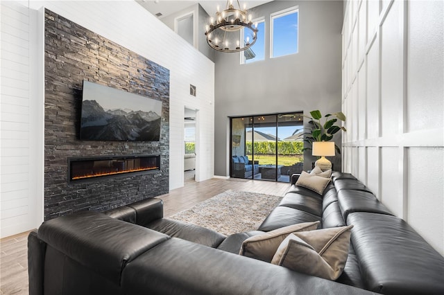 living room with a high ceiling, a chandelier, and a stone fireplace