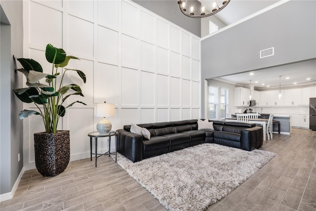 living room featuring a towering ceiling, a notable chandelier, and ornamental molding