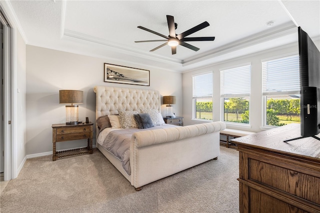 carpeted bedroom with ceiling fan and a tray ceiling