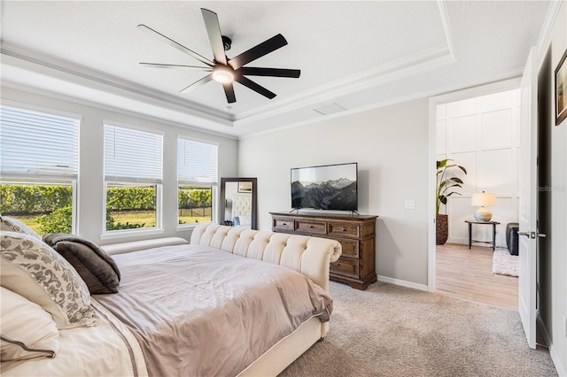 carpeted bedroom with crown molding, ceiling fan, and a raised ceiling