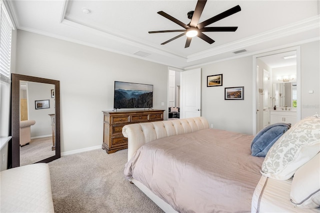 bedroom featuring light carpet, ceiling fan, a tray ceiling, ornamental molding, and connected bathroom