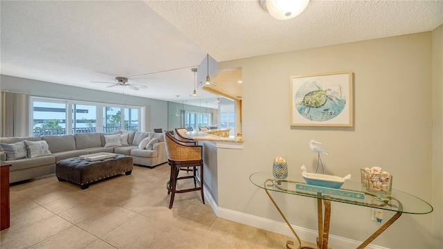 living area featuring a city view, ceiling fan, a textured ceiling, baseboards, and tile patterned floors