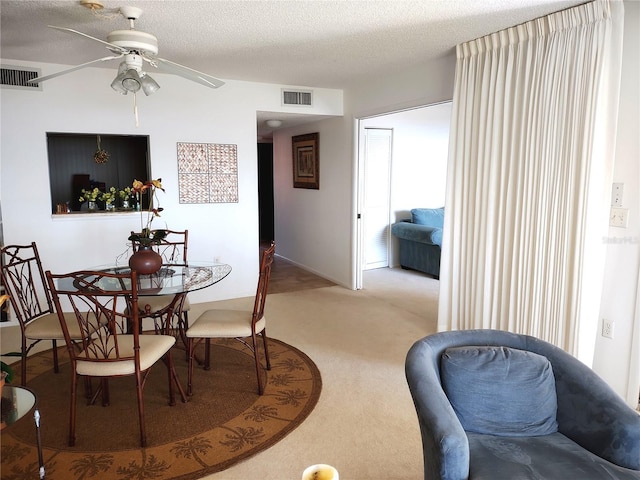 carpeted dining area featuring ceiling fan and a textured ceiling