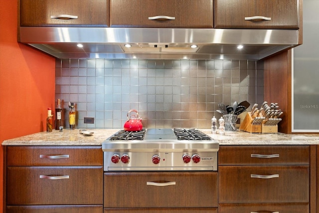 kitchen with light stone counters, stainless steel gas cooktop, tasteful backsplash, and range hood