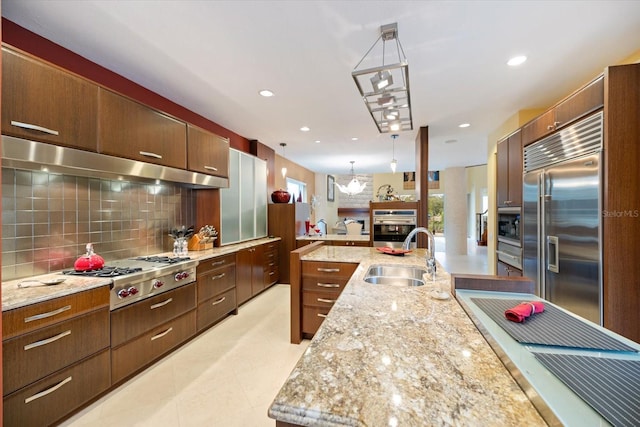 kitchen featuring tasteful backsplash, exhaust hood, sink, hanging light fixtures, and stainless steel appliances