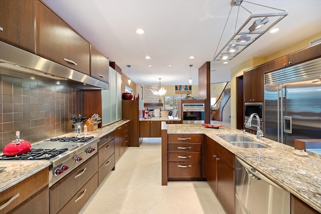 kitchen with an inviting chandelier, stainless steel appliances, tasteful backsplash, pendant lighting, and sink