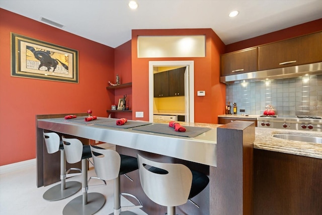 kitchen featuring tasteful backsplash, a kitchen bar, and sink