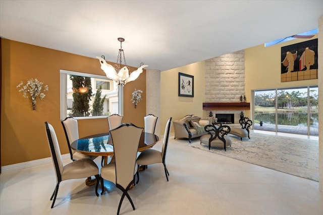 dining room with a large fireplace, a water view, and a chandelier