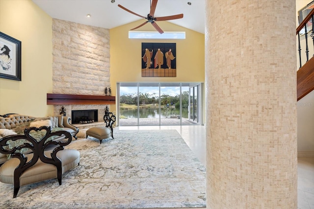 living room featuring ceiling fan, high vaulted ceiling, and a fireplace