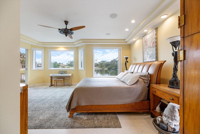 tiled bedroom with ceiling fan and a tray ceiling