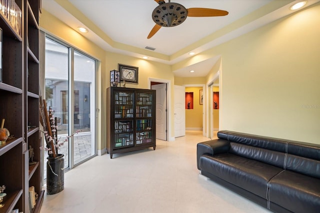 living room with ceiling fan and a tray ceiling