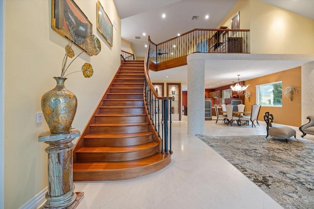 staircase featuring an inviting chandelier, tile patterned floors, and a high ceiling