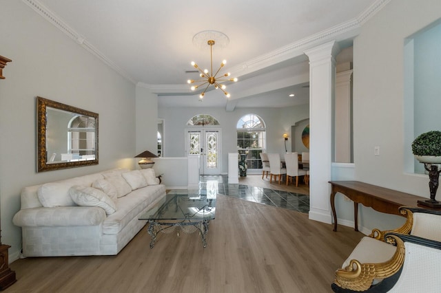 living room featuring french doors, wood-type flooring, crown molding, and a notable chandelier